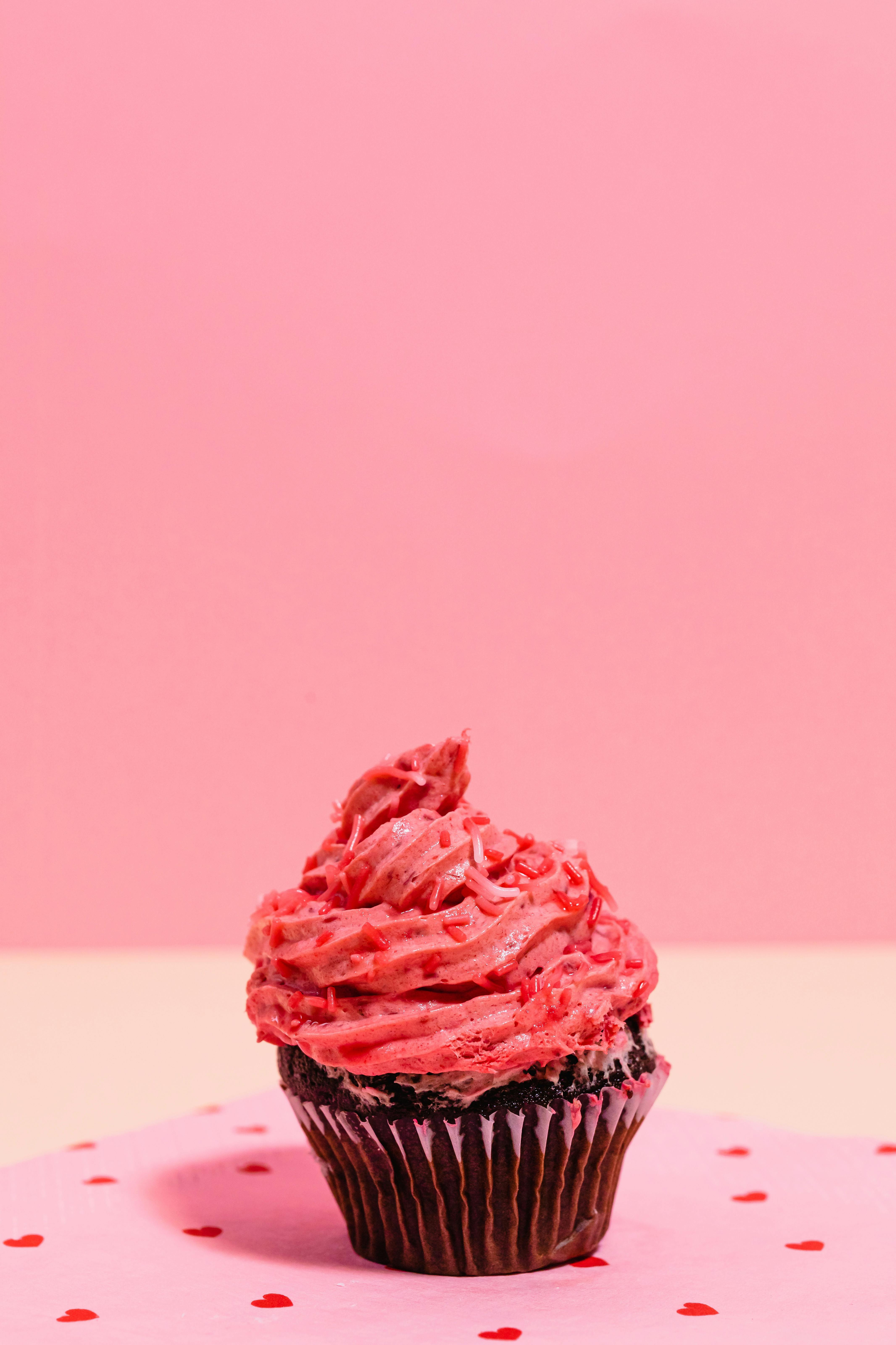 sweet red creamy cupcake on pink background