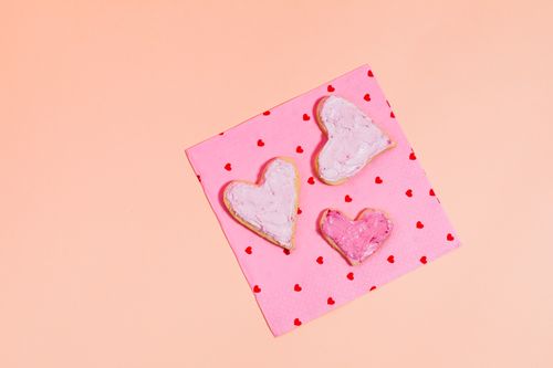 Free Three heart-shaped cookies on a pink napkin with red hearts, perfect for Valentine's Day. Stock Photo
