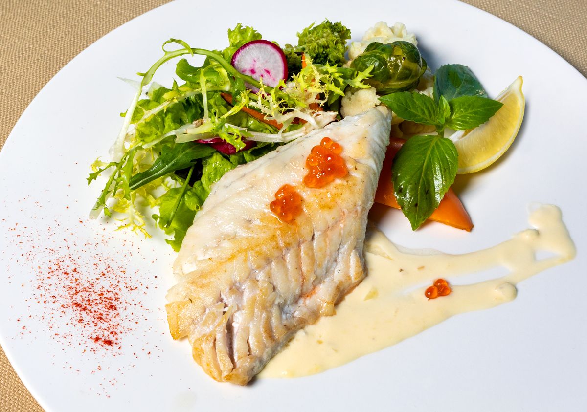 Pan-seared white fish fillet with salmon roe, beurre blanc, frisee salad, radish, basil and lemon