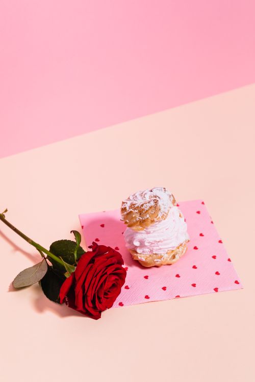 Free Elegantly styled rose and cream puff on heart patterned napkin, perfect for romantic occasions. Stock Photo