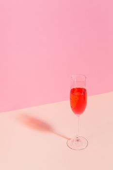 一张以粉红色香槟和酒杯为特色的静物照片，背景为粉红色