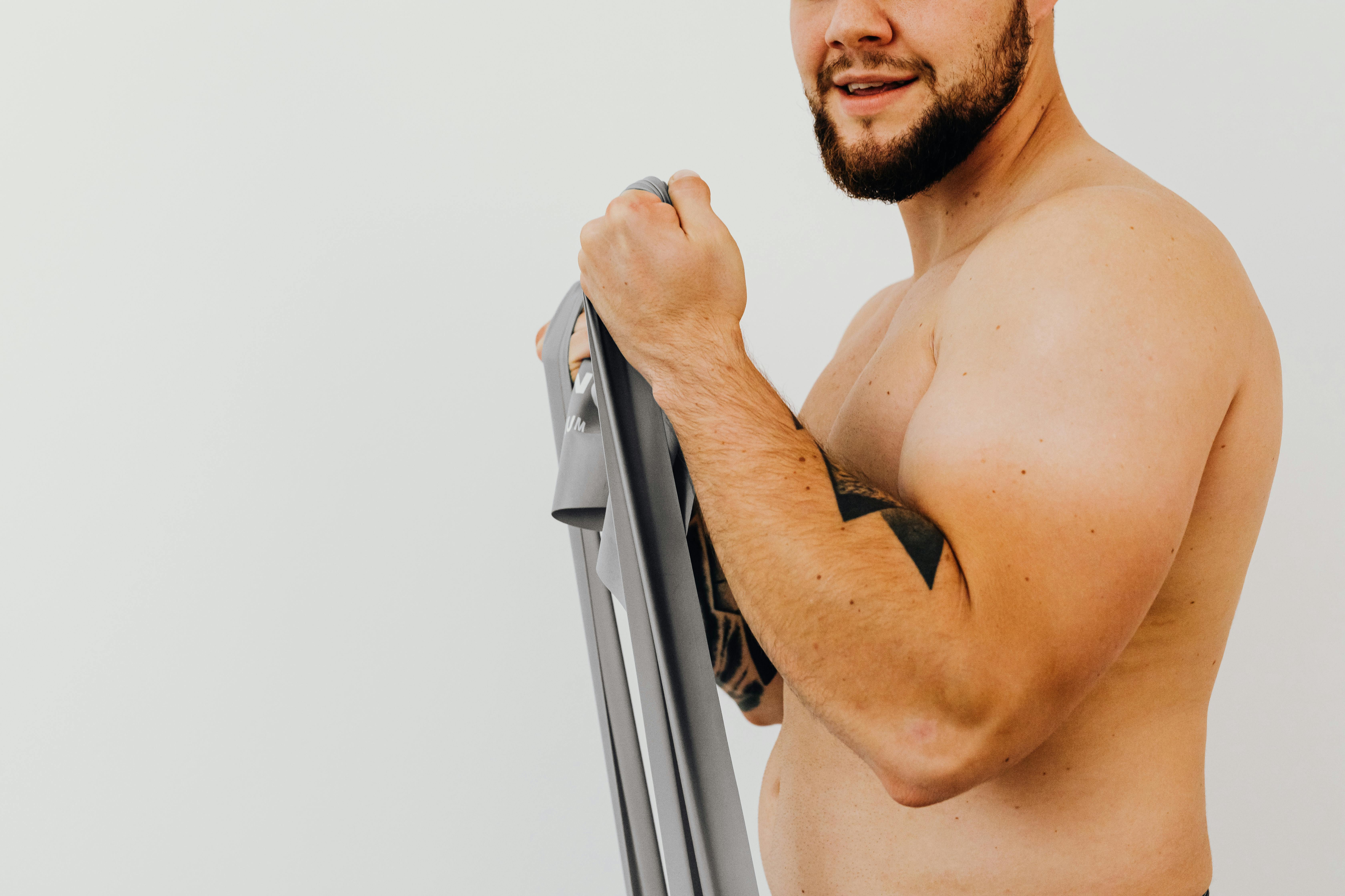 topless man holding a gray exercise equipment