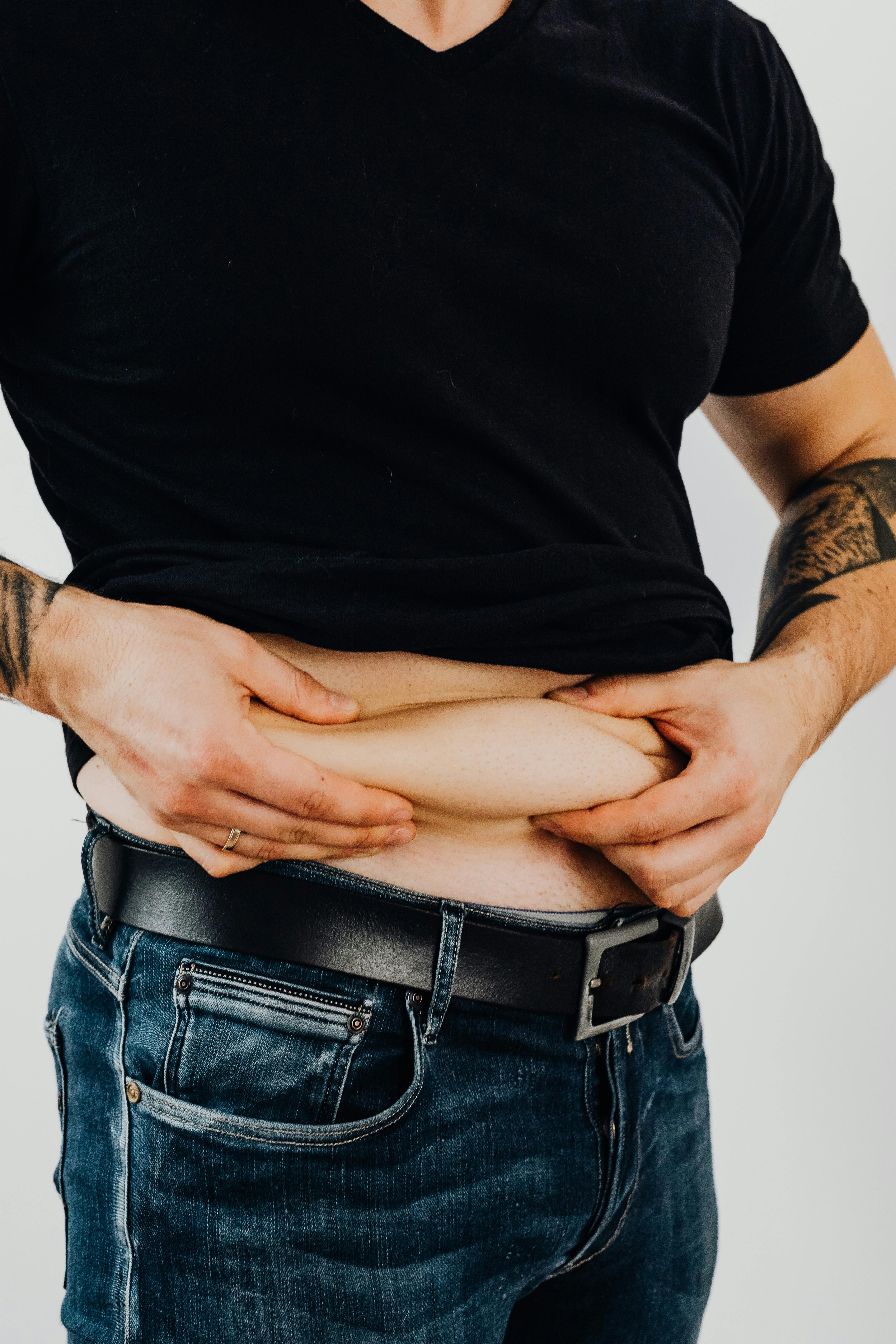Man in black crew neck t-shirt holding his big belly. | Photo: Pexels