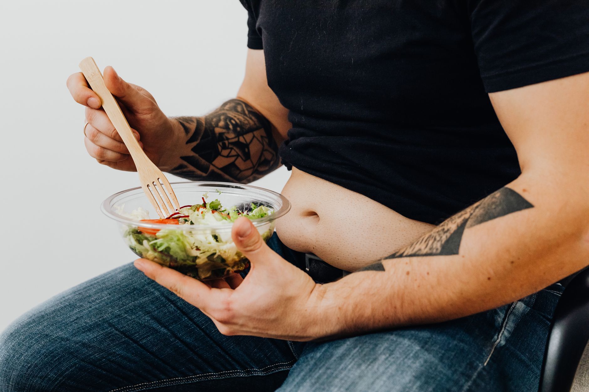 Indian woman measuring waist with measuring tape while checking a healthy meal plan on a table