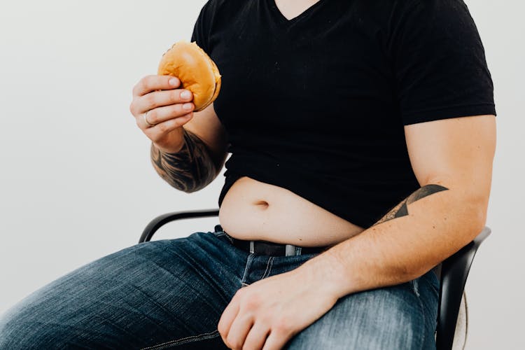 A Man In Black Shirt Holding A Hamburger