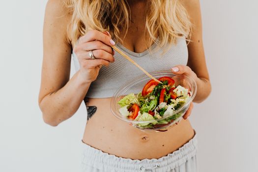 Woman in sports attire enjoys a fresh, nutritious salad, embodying a healthy lifestyle.