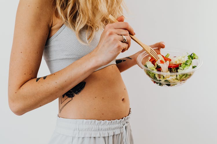 Unrecognizable Blonde Woman Eating Salad From Glass Bowl