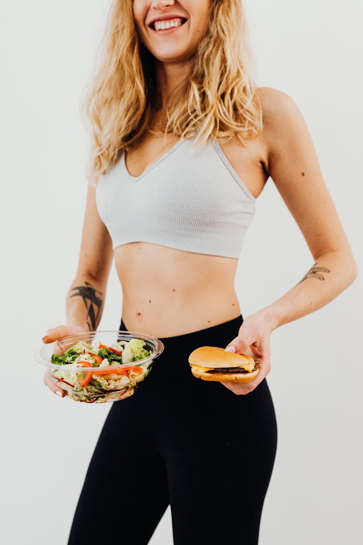 Woman In Sports Bra And Black Leggings Holding Food