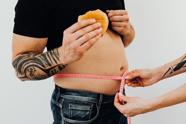 Hands Of A Person Measuring A Man's Waistline