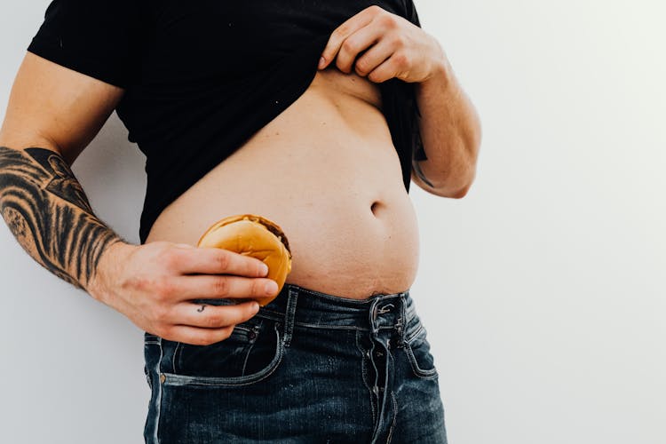 A Man Showing His Belly And Holding A Cheeseburger