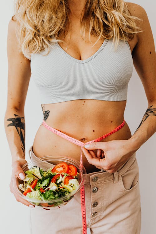 Woman in Crop Top Holding a Tape Measure on Her Waist