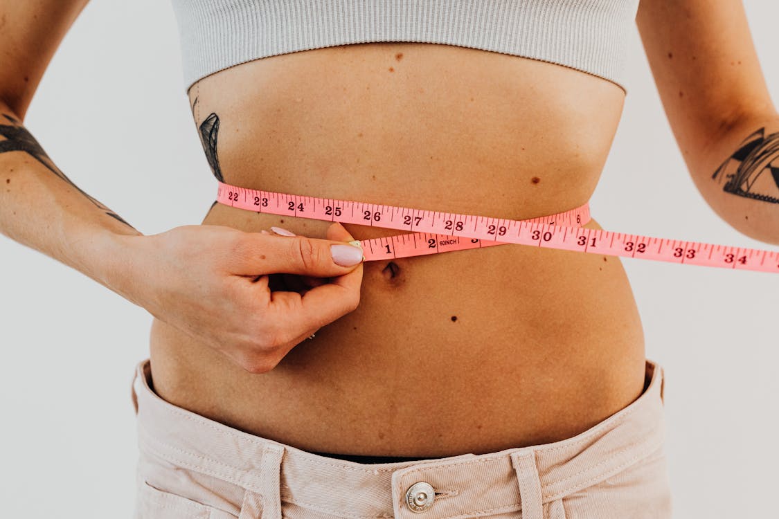 Free Woman Measuring Waistline With a Pink Tape Measure Stock Photo