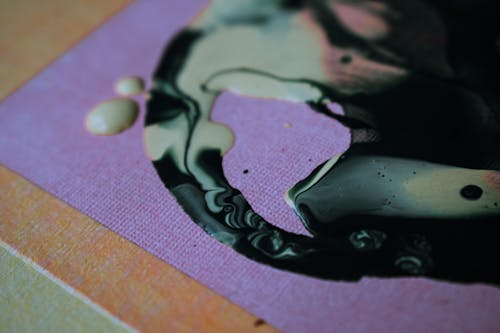Blended black and white pigments spilled on violet cloth