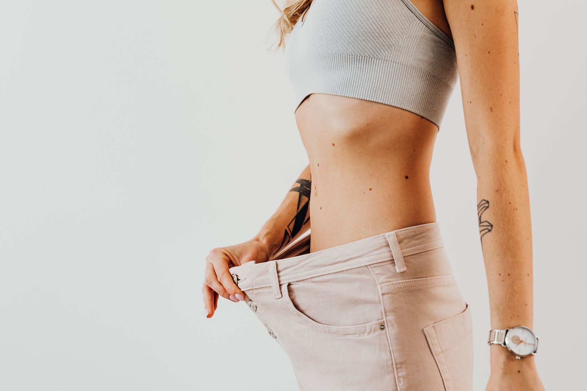 30天減重計畫親測:我減重7公斤的震撼轉變 Close-up of a woman in oversized jeans symbolizing weight loss in a studio setting.