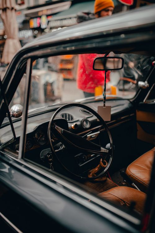 Free Big black round steering wheel and leather beige chairs in cabin of old vintage automobile in daytime Stock Photo