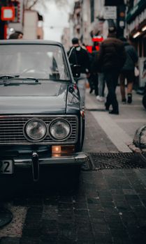 Small round transparent headlights and number on license plate of retro automobile parked on paved street in city in daylight