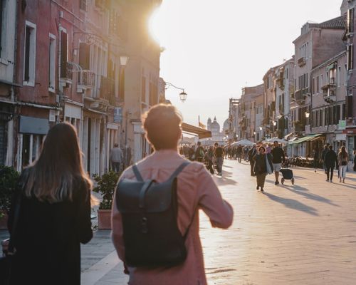 Free People strolling through a picturesque street in Venice at sunset, capturing the urban charm and timeless architecture. Stock Photo