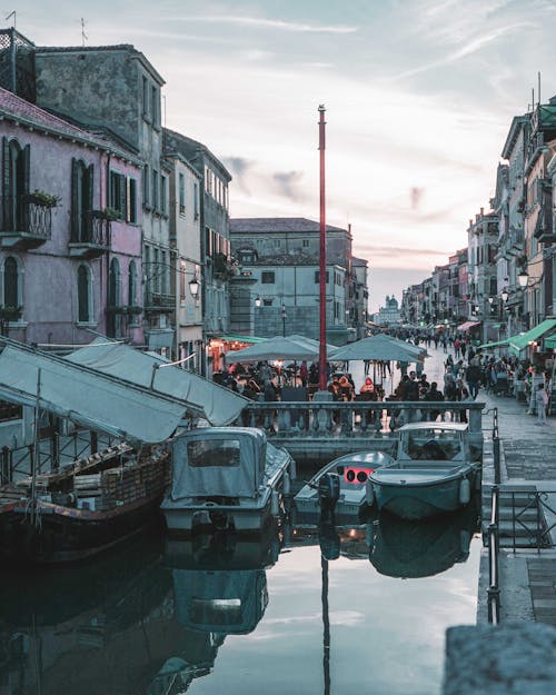 Motorboats Moored on Canal by a Promenade Full of People in Venice Italy