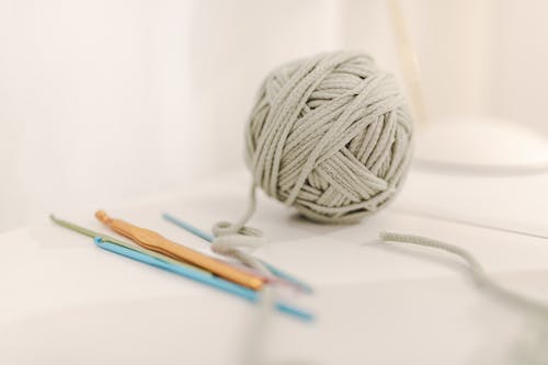 Free Clew of gray knitting threads composed with different crochets on table on white background Stock Photo