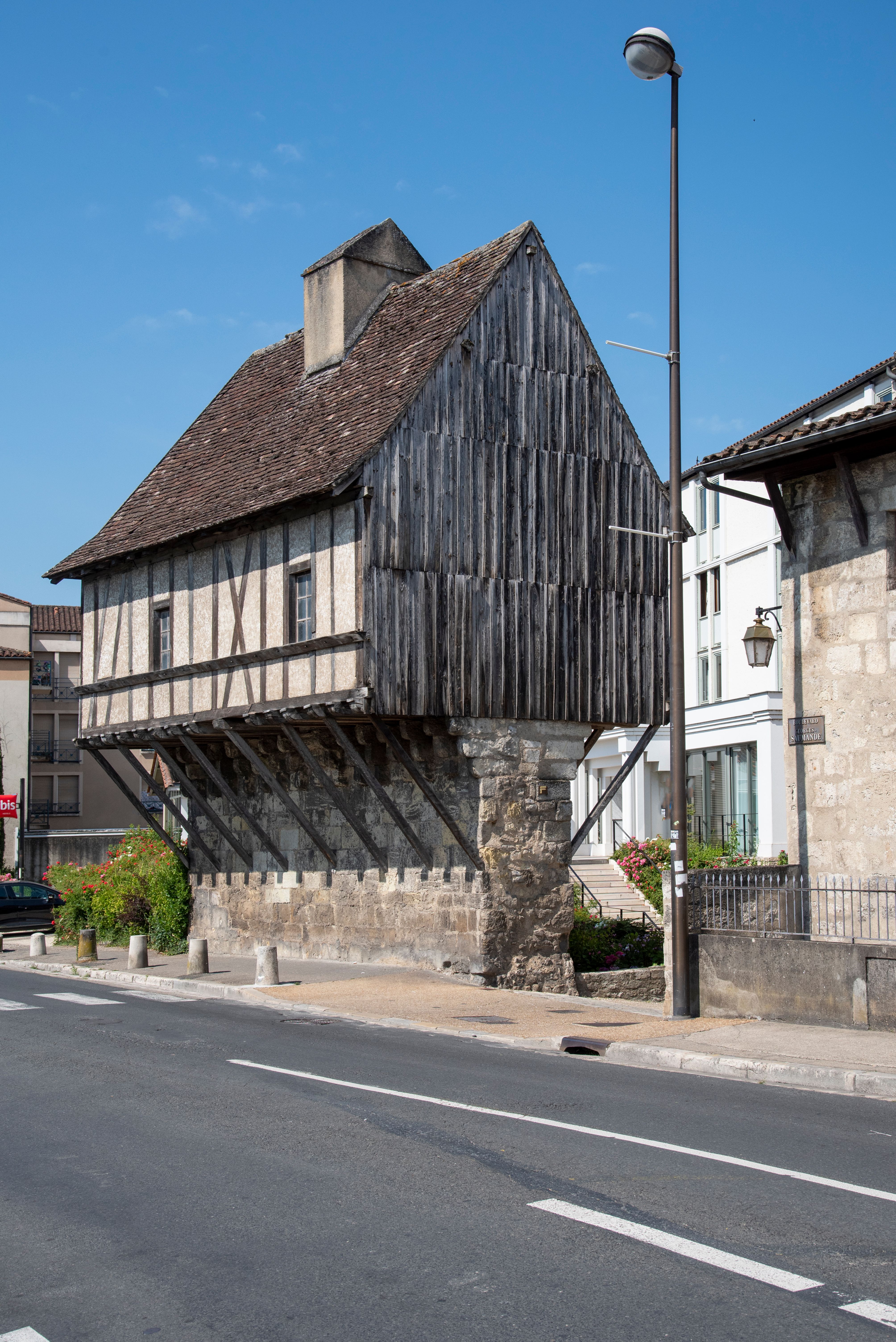 Old timber-framed house on stone pillar in Périgueux, France, showing historic architecture.