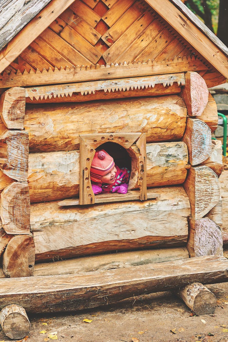 Girl Looking Through Wooden Playhouse Window