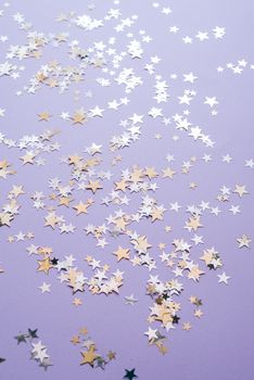 金色和银色的五彩纸屑星星散落在紫色表面上，营造出节日气氛