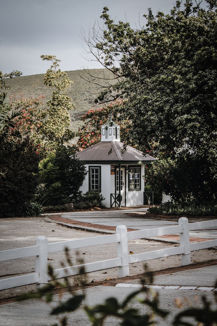 Small House With White Fence Near Hill