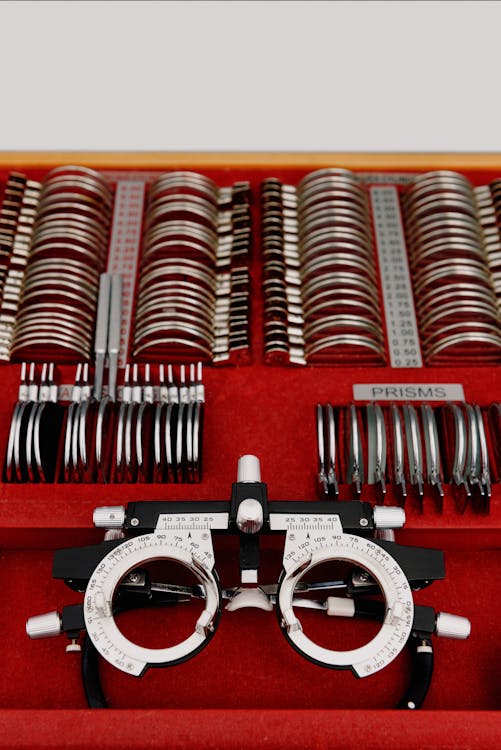 From above optic equipment including trial frame and assorted lenses for eyesight examination placed in red holder in optometry studio