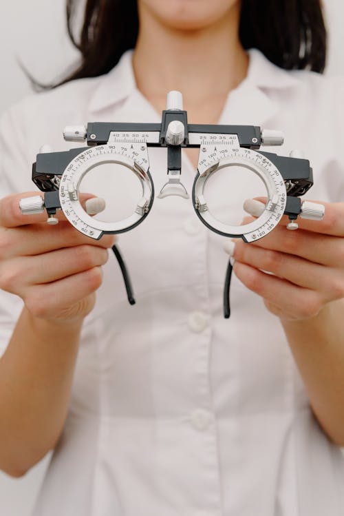 Crop unrecognizable female ophthalmologist showing trial frame with lenses