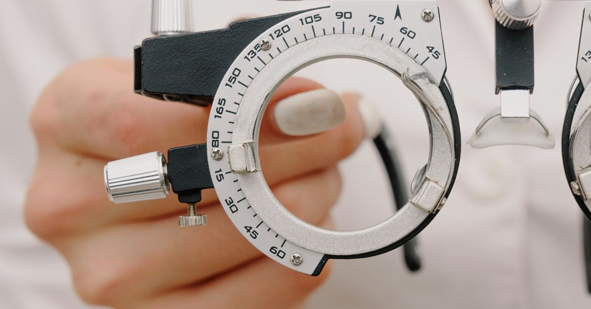 Crop unrecognizable female optometrist with trial frame in hands