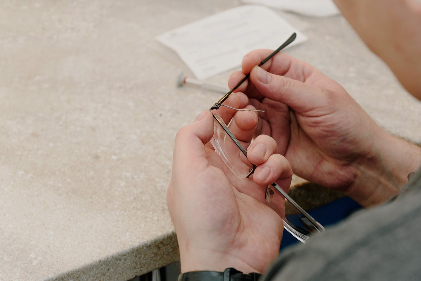Technician fixing eyeglass hinge at workbench