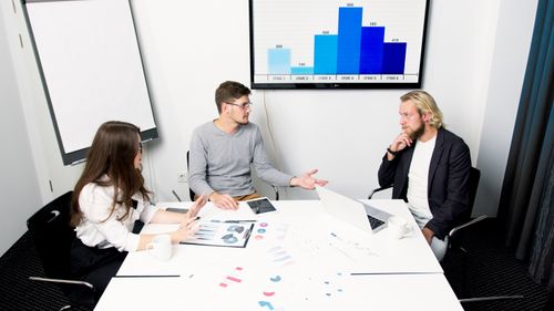 Free Professional team discusses strategies in a modern office environment with digital charts. Stock Photo