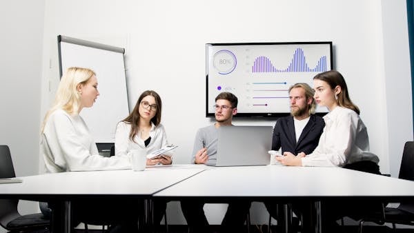 A group of professionals engaged in a business meeting with data presentation