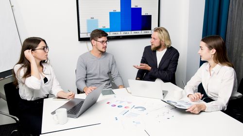 Free A group of business professionals discussing data at a meeting table with laptops and charts. Stock Photo