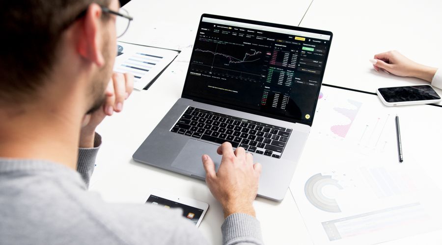 Business professional analyzing stock market data on a laptop, representing disciplined CFD trading strategy review