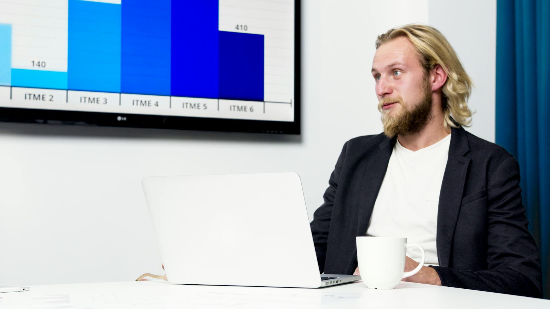 Businessman in a meeting analyzing data on a laptop with a chart on the screen.