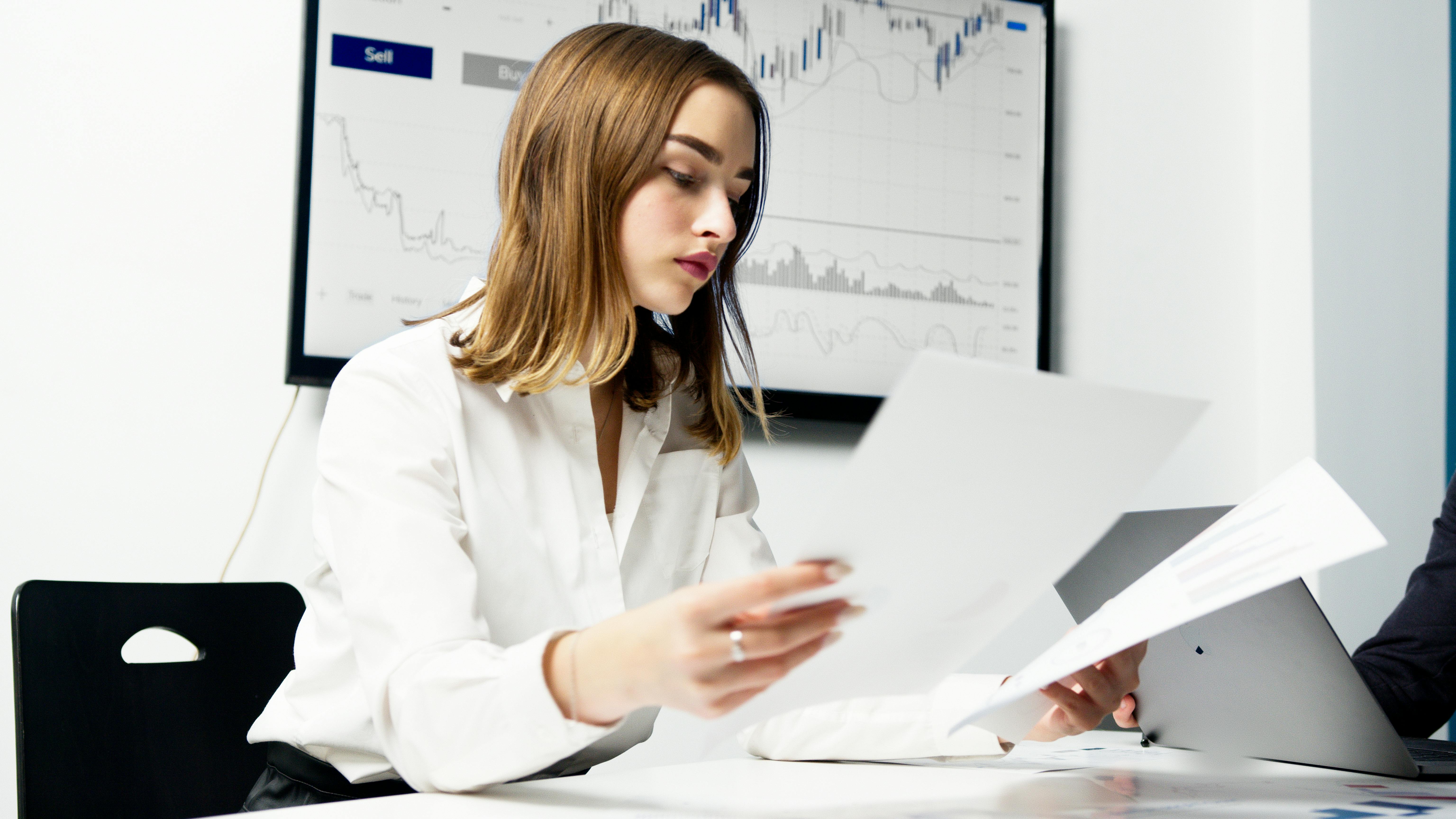 a woman in white dress shirt holding pieces of paper