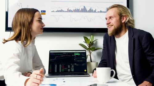 Free A business meeting with two professionals discussing data on laptops with charts displayed. Stock Photo