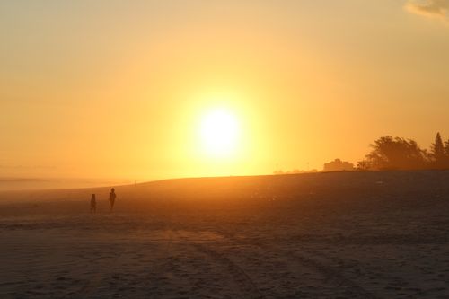 Free Beautiful sunset scene at Saquarema Beach, Brazil, with silhouettes on the sandy shore. Stock Photo