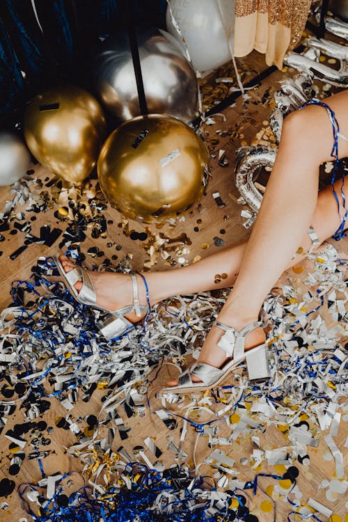 Free Woman in White Leather Peep Toe Sandals Sitting on Gold and Silver Baubles Stock Photo