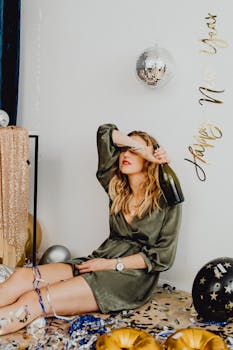 Woman in festive setting with champagne, confetti, and disco ball celebrating New Year's Eve.