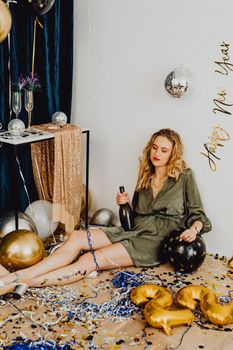 一位金发女子身穿派对礼服，用气球和香槟庆祝新年