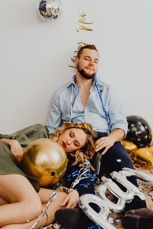 Free Couple asleep among New Year's Eve party decorations, including balloons and confetti. Stock Photo