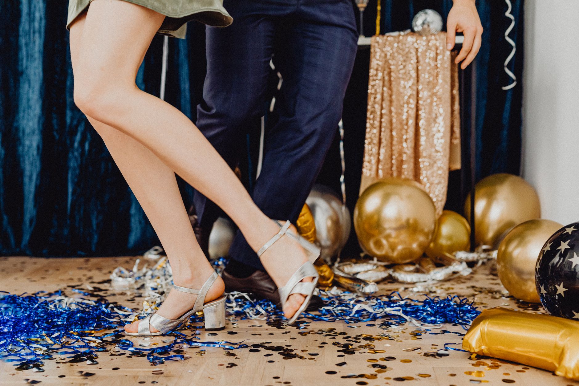Anniversary Party Songs That Bring Every Generation Together A couple dancing amidst golden balloons and confetti at a vibrant indoor party.