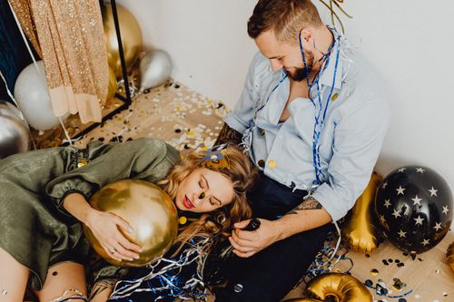 Free A couple relaxes amidst party decorations, surrounded by balloons and confetti. Stock Photo