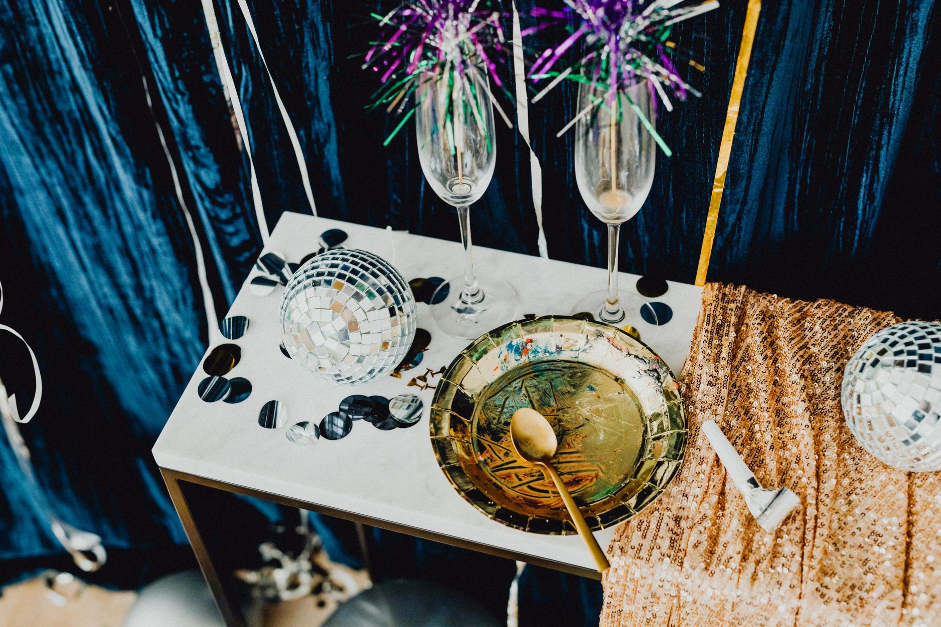 Elegant table setting with champagne, disco balls, and festive decorations for a celebration.