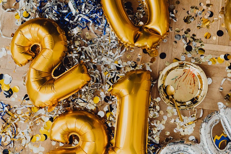 A Gold Balloons With Confetti Scattered On The Floor