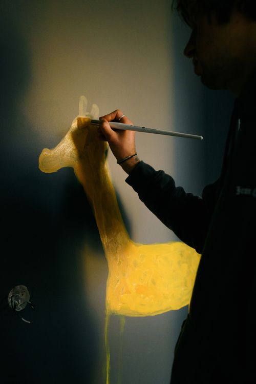 Free Side view crop male in workwear drawing yellow animal on dark wall in kid bedroom Stock Photo
