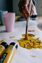 Crop faceless artist sopping paintbrush in yellow paint