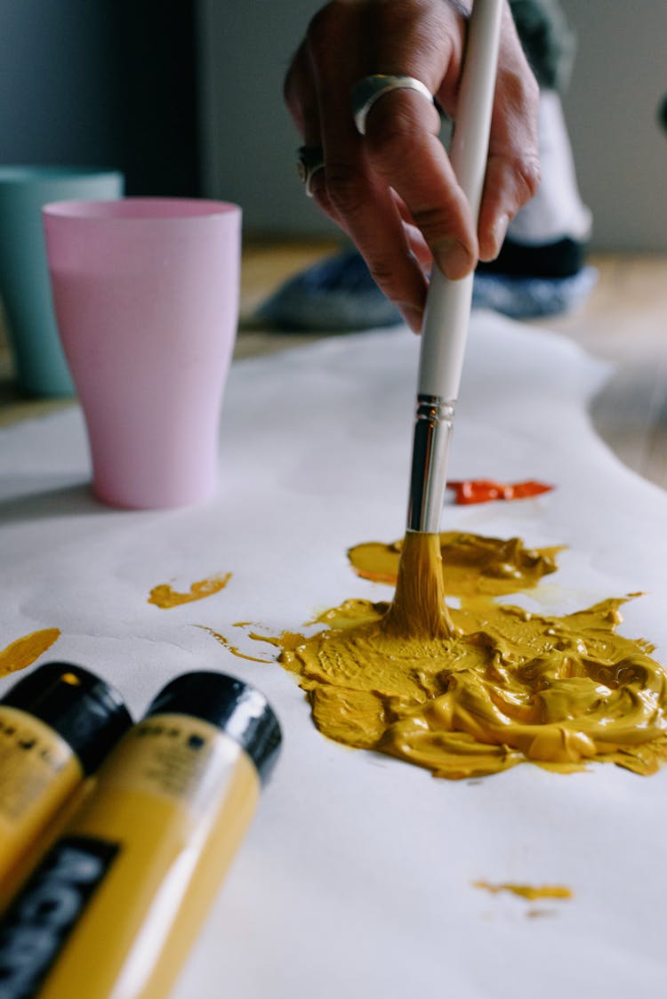 Crop Faceless Artist Sopping Paintbrush In Yellow Paint